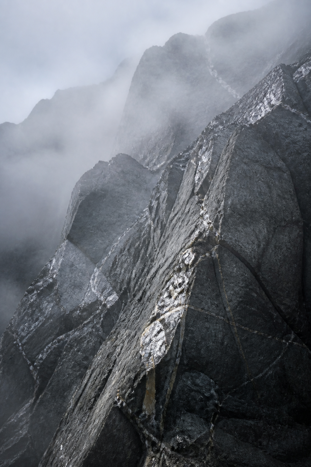 Misty gray mountain face with pale mineral veins and crystalline stone